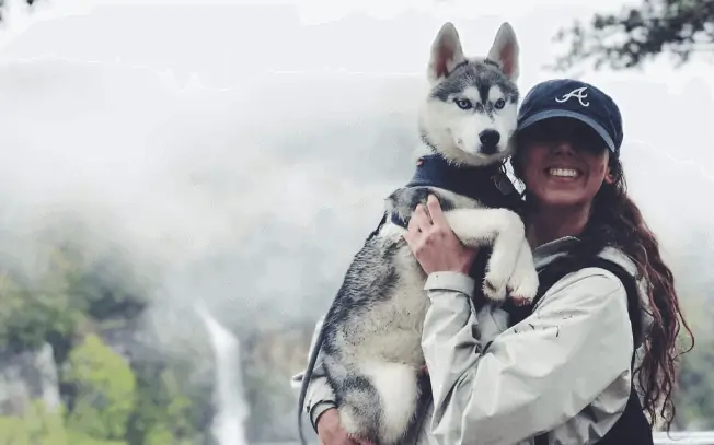 Girl holding a husky puppy outdoors