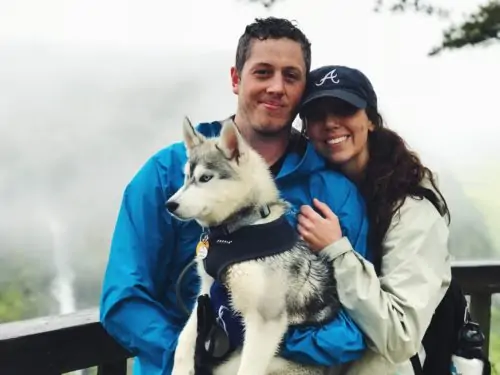 Man and woman holding husky dog smiling at camera