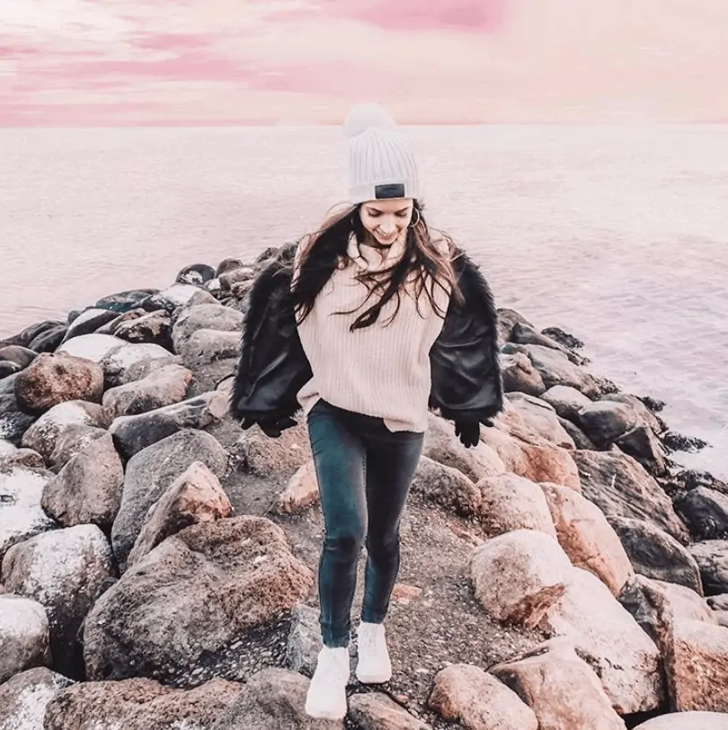 Girl walking on rocks with ocean behind